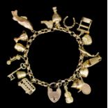 A modern 9ct gold bracelet with oval reeded links, hung with eighteen charms, 190mm overall (gross