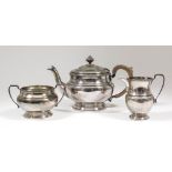 A George V silver circular three piece tea service, the moulded rims cast with oval bead ornament,