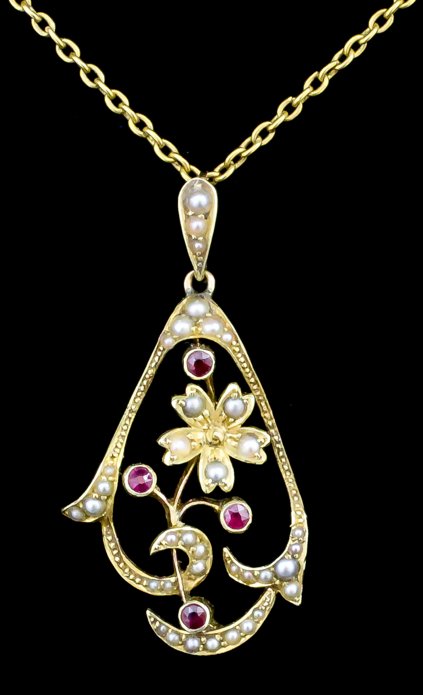 An Edwardian 15ct gold seed pearl and garnet set pendant, of scrolling form the seed pearl set