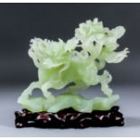 A Chinese green hardstone figure of a dragon on rocky base, 8ins (20.3cm) overall x 6.75ins (17.2cm)