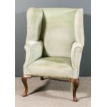 A 20th Century walnut wing back easy chair of "18th Century" design, the high back with bold