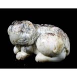 A Chinese white jade carving of archaistic form of a crouching Kylin, with black and pink mottling