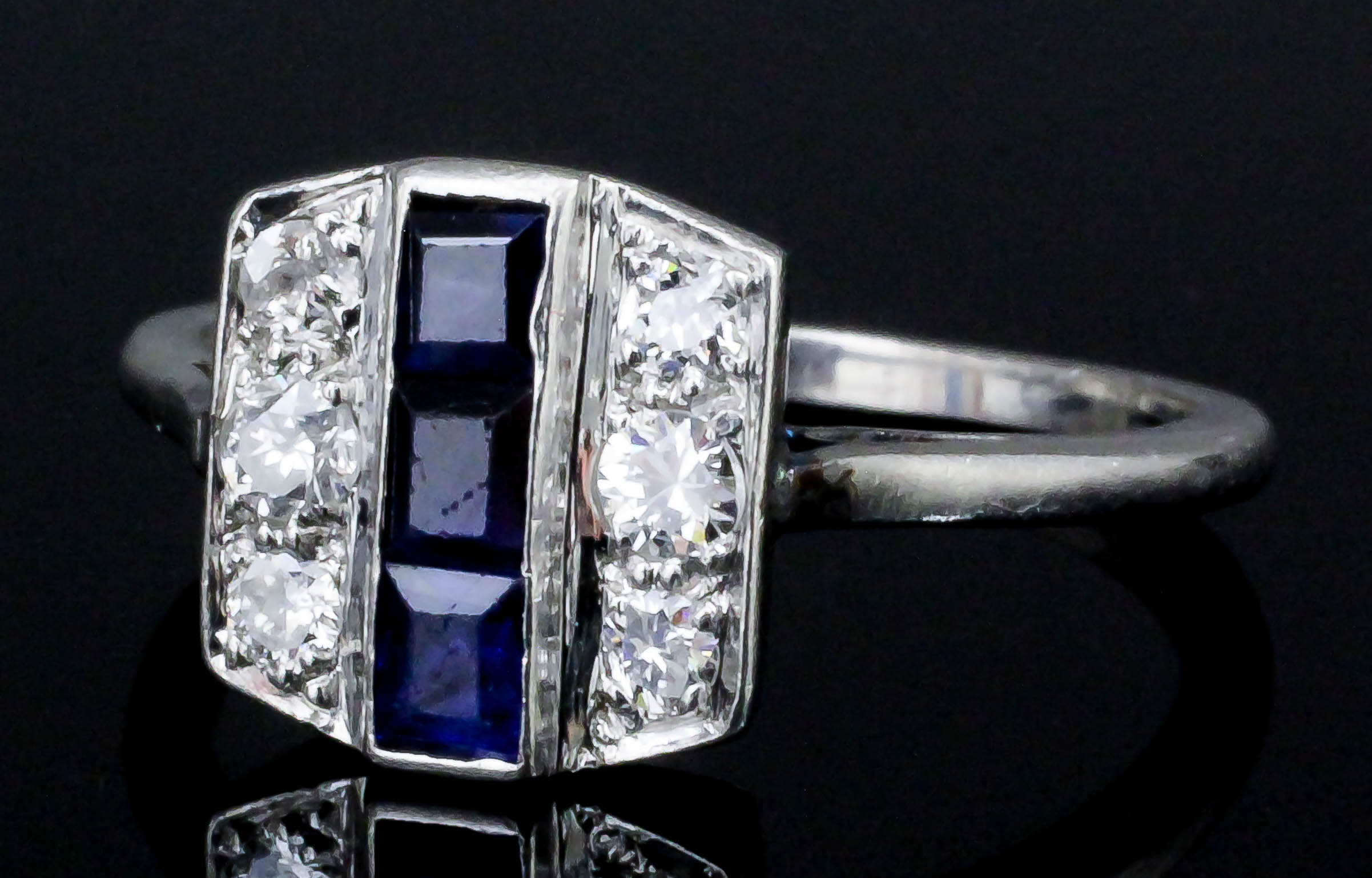 An Art Deco platinum mounted sapphire and diamond ring, the face channel set with three baguette cut