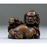 A Japanese carved boxwood netsuke in the form of two children cowering away from a standing child