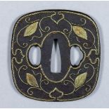 A Japanese iron tsuba of the Kaga school, inlaid in gilt brass with trailing leaves within a rope