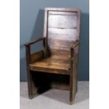 An 18th Century pine and oak armchair with panelled back and seat, on square legs (somewhat