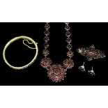 A late Victorian gold coloured metal mounted garnet set suite of jewellery, comprising -