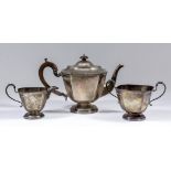 A George V silver octagonal three piece tea service of panelled form, with C-scroll handles and on
