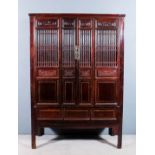 A Chinese stained wood and panelled cabinet with moulded cornice, fitted one shelf and four drawers,