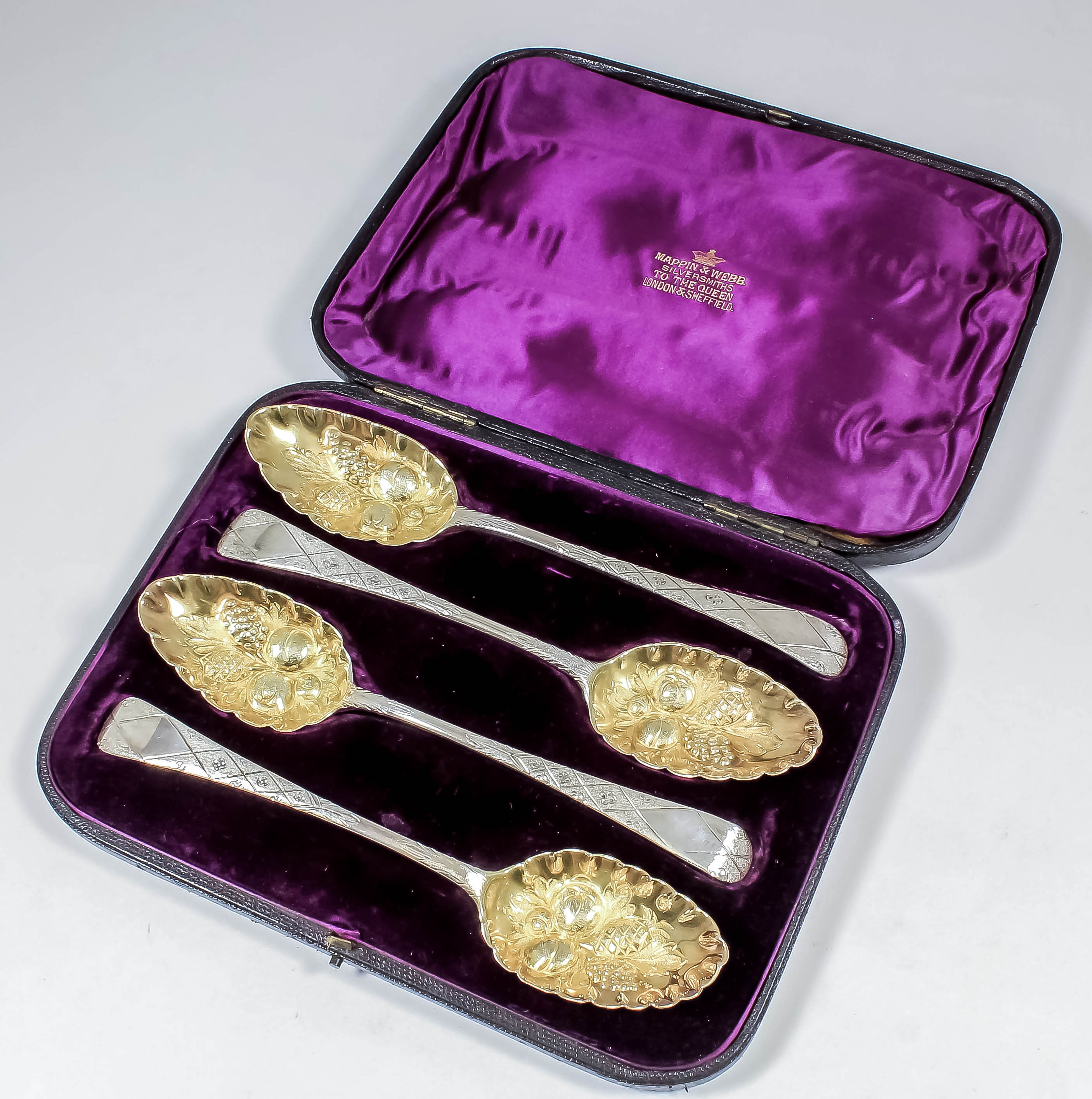 A set of four George III silver and silver gilt "Berry" spoons, the handles chased and engraved with