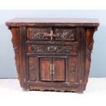 A Chinese stained wood dwarf cabinet with flush panel to top, the front carved with leaf ornament,