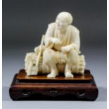 A Japanese carved ivory Okimono of a woodcutter seated on a bundle of twigs, a tinder pouch and