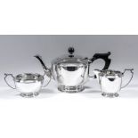 A George V silver circular three piece tea service with reeded mounts, plain bodies, angular