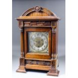 A late 19th Century German walnut cased mantel clock, the brass dial with 5.5ins diameter silvered