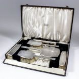 A George VI silver backed six piece dressing table set of "Art Deco" design, the engine turned backs