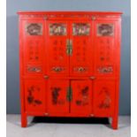 A Chinese red lacquer and gilt decorated two tier cabinet with four panels to front, the upper