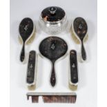 A George V silver and tortoiseshell backed six piece dressing table set, the tortoiseshell inlaid in