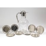 A plated, mounted and clear glass claret jug, the domed lid with shaped thumbpiece, plain scroll