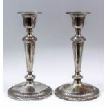 A pair of George V silver pillar candlesticks with fluted sconces and tapered stems, on circular