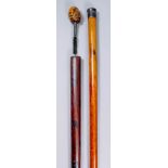 A 19th Century novelty walking cane, the black painted brass top with clear glass showing two