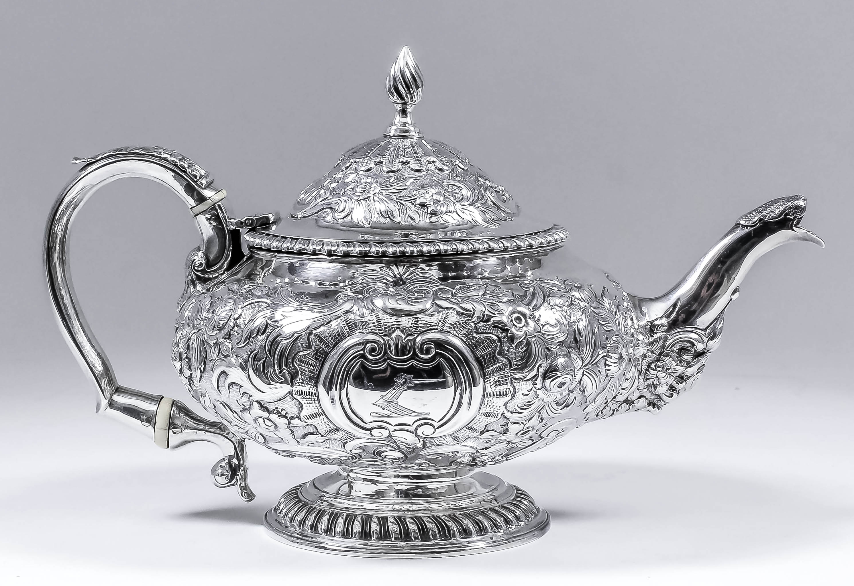 A George IV silver circular teapot of bulbous squat form, with gadroon mounts, the whole embossed