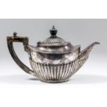 An Edward VII silver oval teapot with part reeded lid and body, ebonsied angular handle and