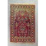 A Tabriz rug woven in colours with urns of flowers, within Mihrab and on a dark wine ground,