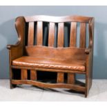 An early 20th Century oak wing back settle with shaped crest rail and moulded splats to back,