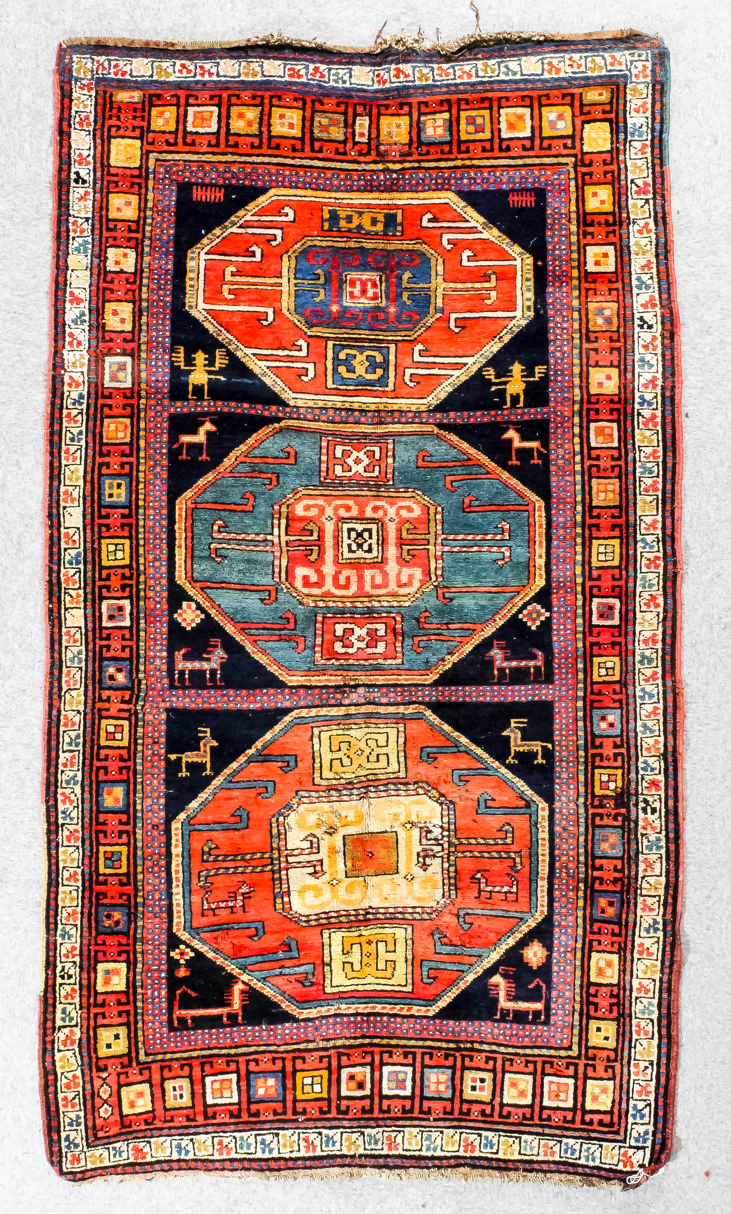 A Kazak Karachop rug woven in colours with three bold octagonal motifs, animals and samovars, on a