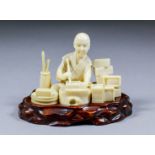 A Japanese carved sectional ivory Okimono of a seated box maker, 2.5ins (6.4cm) high (lacking seal