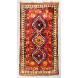 A Kazak rug woven in colours with a central triple medallion edged with hooked motifs, within border