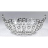 A George V silver circular two-handled basket with shaped rim and pierced oval panels, cast wreath