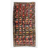 A Karabakh long rug woven in blue, rose, orange and fawn with numerous armorial style motifs, on a