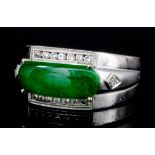 A modern 18k white gold mounted jade and diamond ring, the oblong cut jade panel, 15mm x 5mm