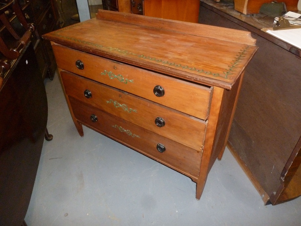 A SATIN WALNUTWOOD CHEST OF THREE LONG DRAWERS WITH PAINTED FOLIATE BORDER AND RIBBON BOWS TO THE