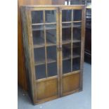 1930'S OAK BOOKCASE ENCLOSED BY TWO GLAZED PANE PANEL DOORS. HEIGHT 146CM, LENGTH 89CM.