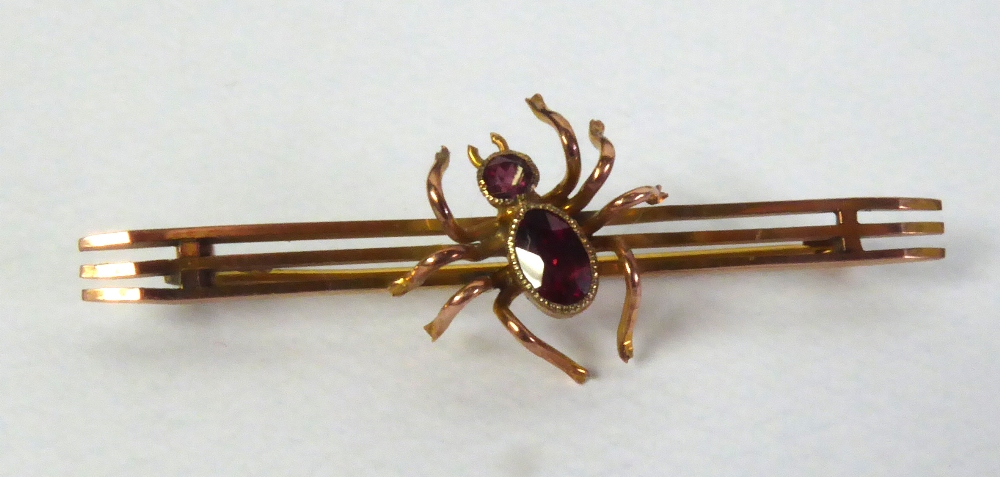 9ct GOLD TRIPLE BAR BROOCH, surmounted by a centre spider set with an oval garnet body and a