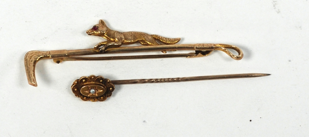 9 CT GOLD BAR BROOCH IN THE FORM OF A RIDING CROP and a running fox with inset ruby eye,