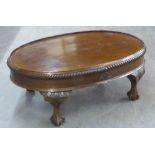 A MAHOGANY OVAL COFFEE TABLE WITH GALLERY BORDER, ON CURVED STUMP CABRIOLE SUPPORTS, CLAW AND BALL