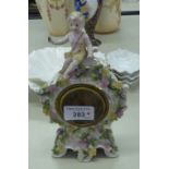 CONTINENTAL CHINA SMALL ROCOCO MANTEL CLOCK WITH PUTTI SURMOUNTING, 8" HIGH (A.F.)