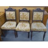 A SET OF THREE EDWARDIAN CARVED OAK DINING CHAIRS WITH UPHOLSTERED BACK PANEL AND SEATS, BALUSTER