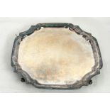 A SILVER SQUARE SALVER incuse corners and moulded border, raised on four acanthus feet, 13 1/2"