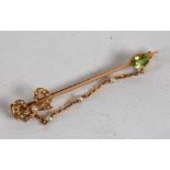 9CT GOLD BAR BROOCH with seed pearl set openwork bow at one end and oval peridot to the other and