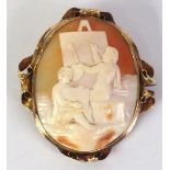 A LATE VICTORIAN UNMARKED GOLD MOUNTED CARVED SHELL CAMEO BROOCH depicting two putti drawing and