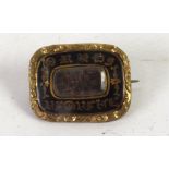 VICTORIAN SMALL OBLONG ROLLED GOLD AND BLACK ENAMELLED MEMORIAL BROOCH with glazed hair locker front