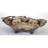 LATE VICTORIAN ELECTROPLATED SWING HANDLED CAKE BASKET, oval form with wavy rim and scroll feet,