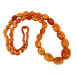 A LONG SINGLE STRAND NECKLACE of opaque honeycomb coloured amber graduated oval beads, approx 42"