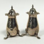 EDWARDIAN VII PAIR OF SILVER PEPPERETTES of baluster form with cyma borders and scroll supports with