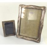 TWO SILVER FRONTED OBLONG PHOTOGRAPH FRAMES, with easel supports, one of wavy outline, 9" x 6 3/