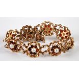 9ct GOLD BRACELET with eight floral links each set with a centre pearl and surround of six